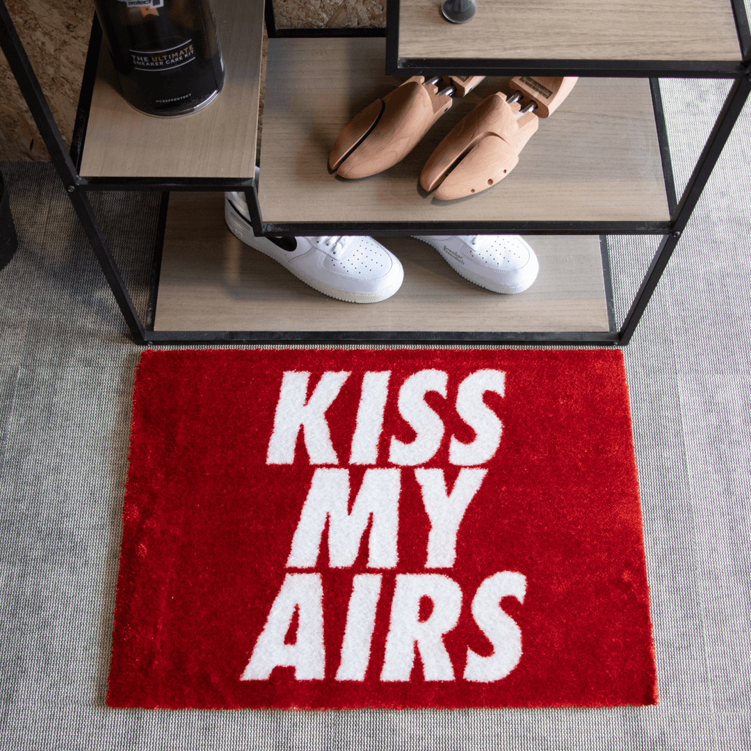 a red rug with white text on it and shoes on a shelf